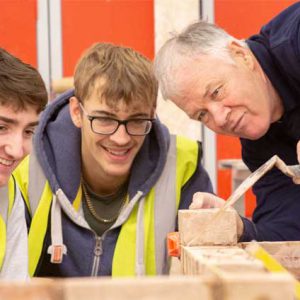 two bricklaying students with lecturer