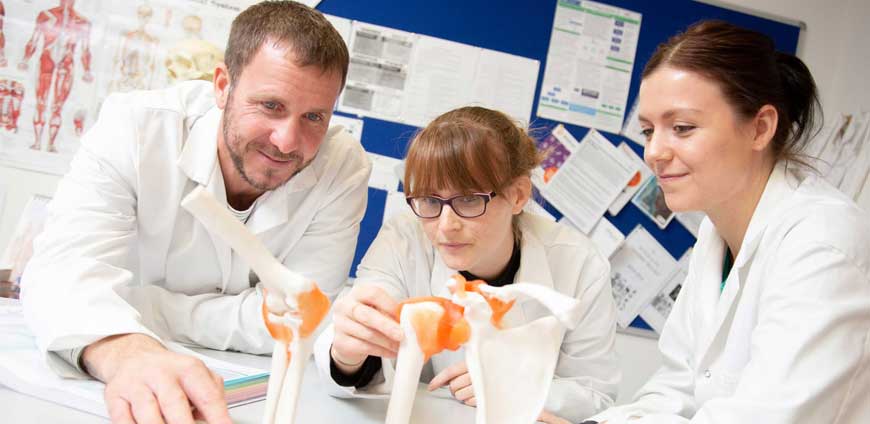 three students looking through microscope