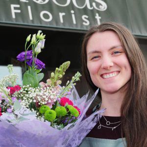 Eleanor Holt holding a bouquet in front of her shop