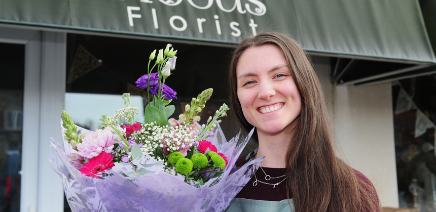 Eleanor Holt holding a bouquet in front of her shop