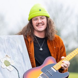 John Hancock holding a guitar and his painting of a flower