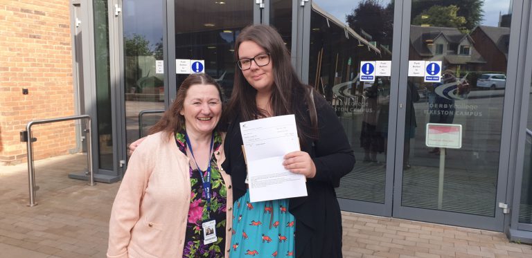GCSE student Lauren holds qualifications aloft next to teacher Caroline
