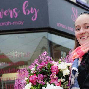 Sarah Anderson holding a bouquet in front of her shop