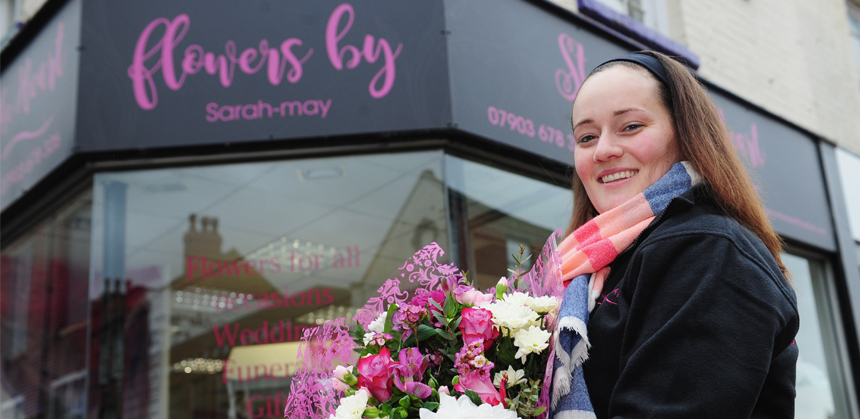 Sarah Anderson holding a bouquet in front of her shop