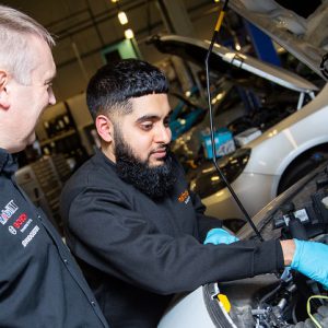 Suhayl Bhikha working on a cars engine under the supervision of his manager