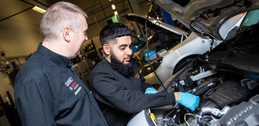Suhayl Bhikha working on a cars engine under the supervision of his manager