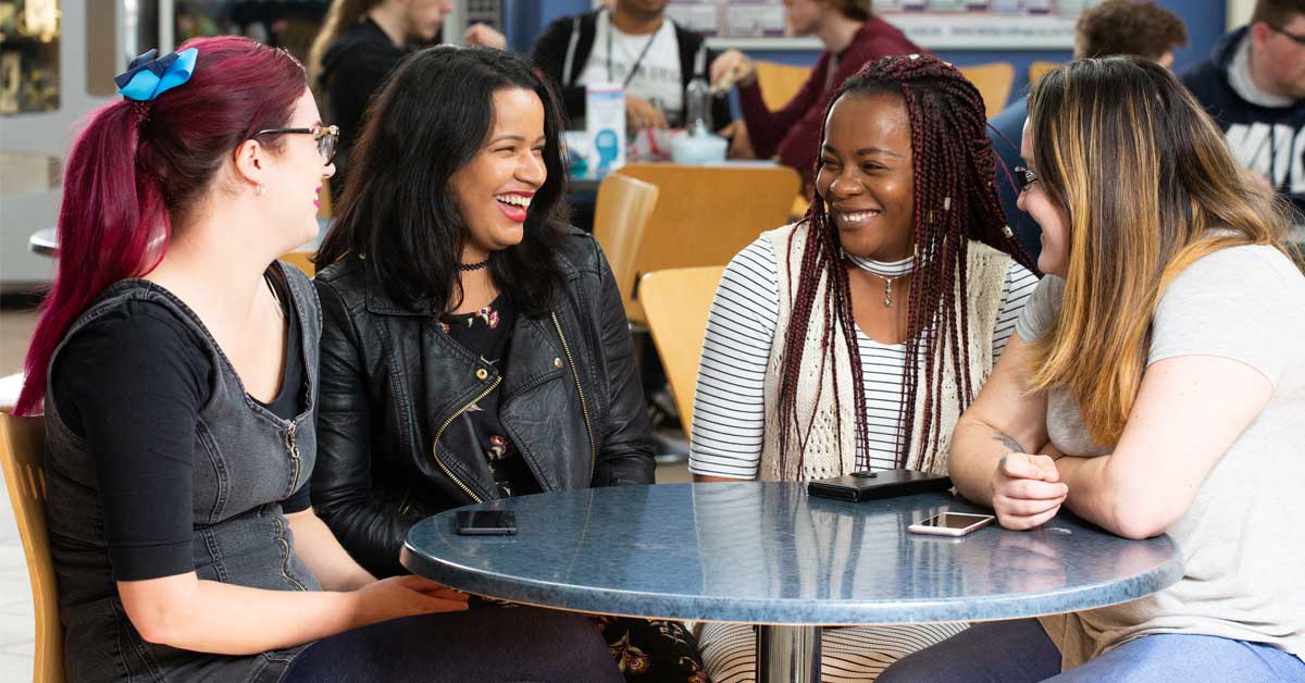 Four female adult students smiling round a table
