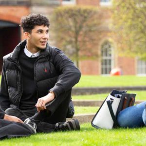 students sitting on the grass in front of the roundhouse