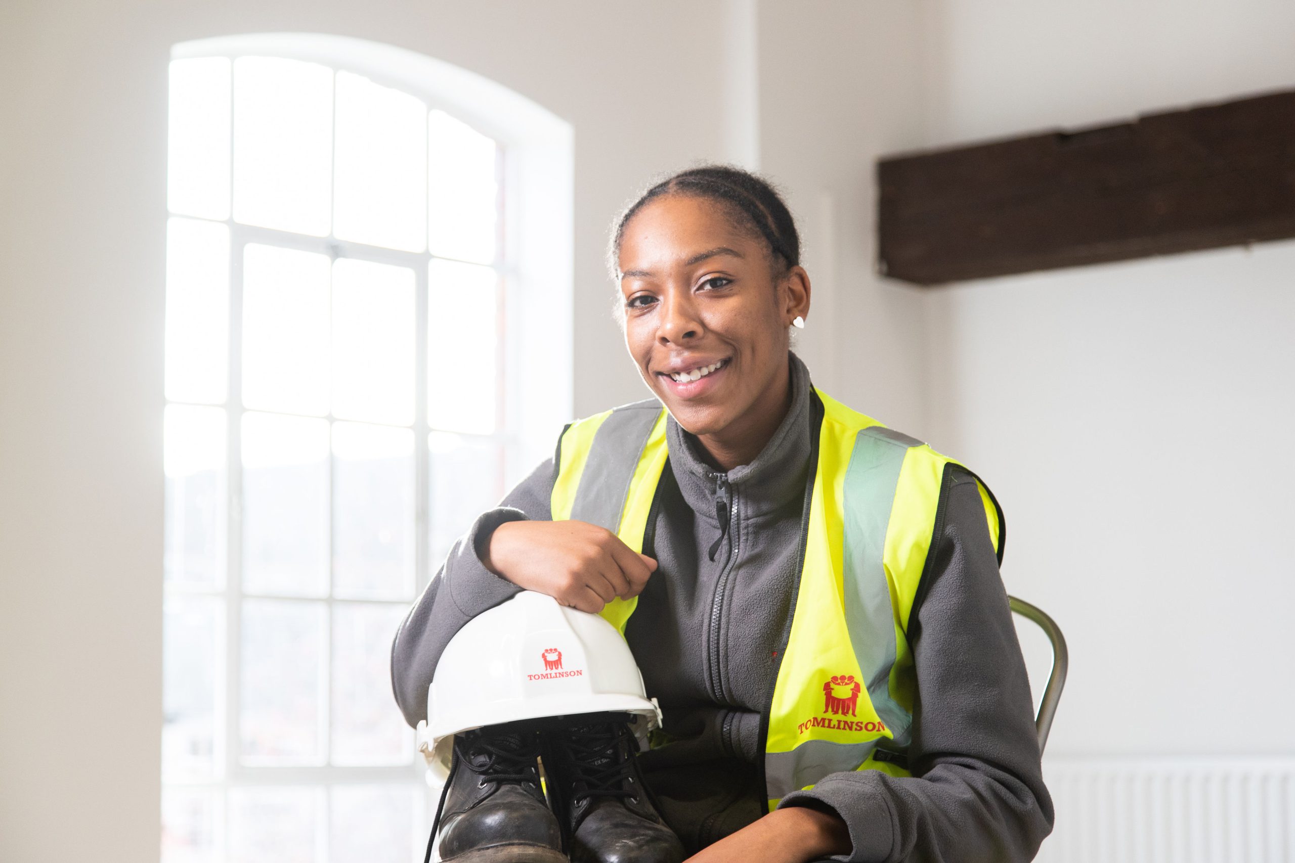 Tiarna Powell wearing a hi-vis vest and holding a hard hat and steel toe-capped boots