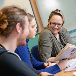 Older teacher helping two younger students