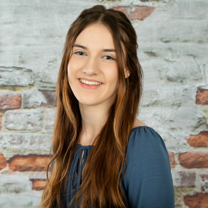 Apprentice Carys Hughes stood against a brick wall.