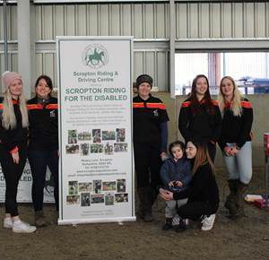 Equine students at Broomfield Hall stood next to a banner for Scropton Riding for the Disabled.