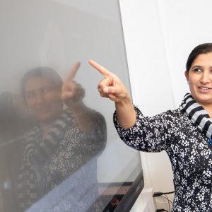 Derby College student and teacher Salwa Khan pointing at text on a whiteboard.