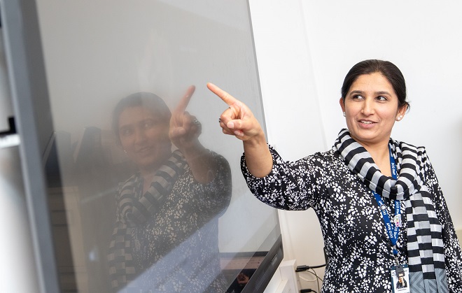Derby College student and teacher Salwa Khan pointing at text on a whiteboard.