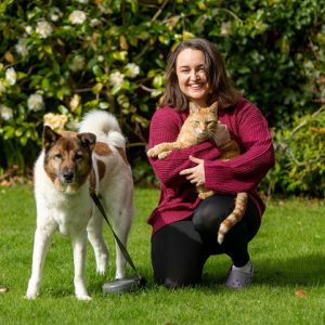 Former Derby College Animal Care student Kate Howell crouched next to a dog whilst holding a ginger cat