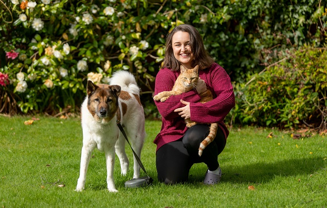 Former Derby College Animal Care student Kate Howell crouched next to a dog whilst holding a ginger cat