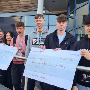 A-level and GCSE Plus students holding their Rag Week cheques in front of The Joseph Wright Centre.