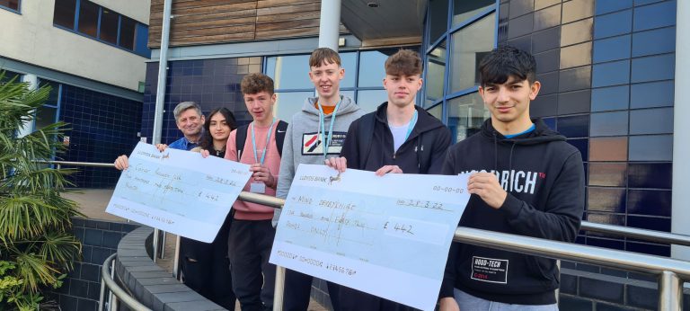 A-level and GCSE Plus students holding their Rag Week cheques in front of The Joseph Wright Centre.