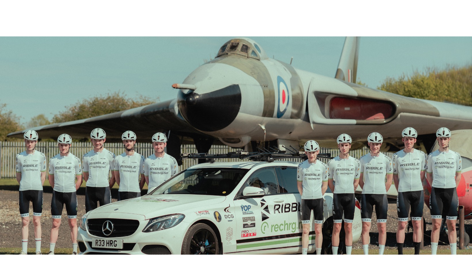 Members of the RIBBL Rechrg team stood by a car and in front of a jet.