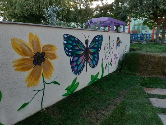 Wall from The Metamorphosis Garden with a blue butterfly and a sunflower painted on it.