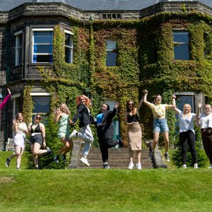 T Level Childcare students jump in the air holding their certificates.