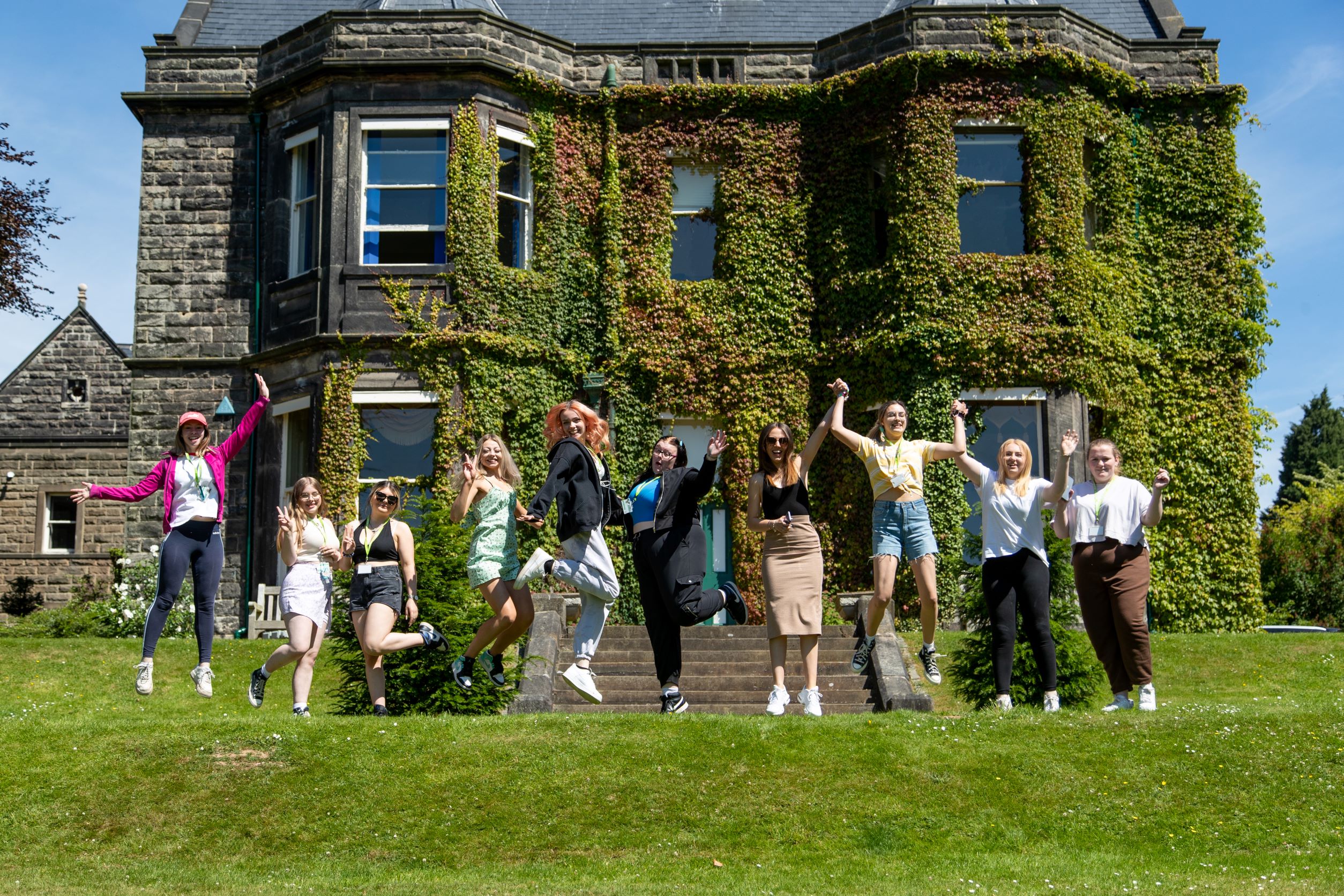 T Level Childcare students jump in the air holding their certificates.