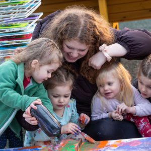 Little Explorers staff member playing with the children in the forest at Broomfield Hall.