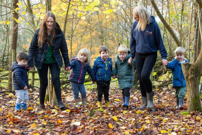 Little Explorers staff walking with children in the forest at Broomfield Hall.