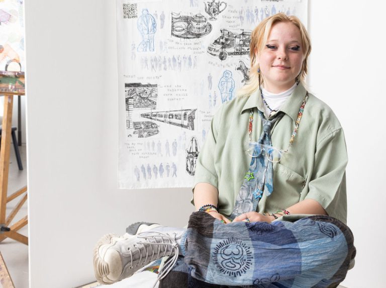 Amy Higginbottom sat infront of her artwork (winner of the bursary Award).