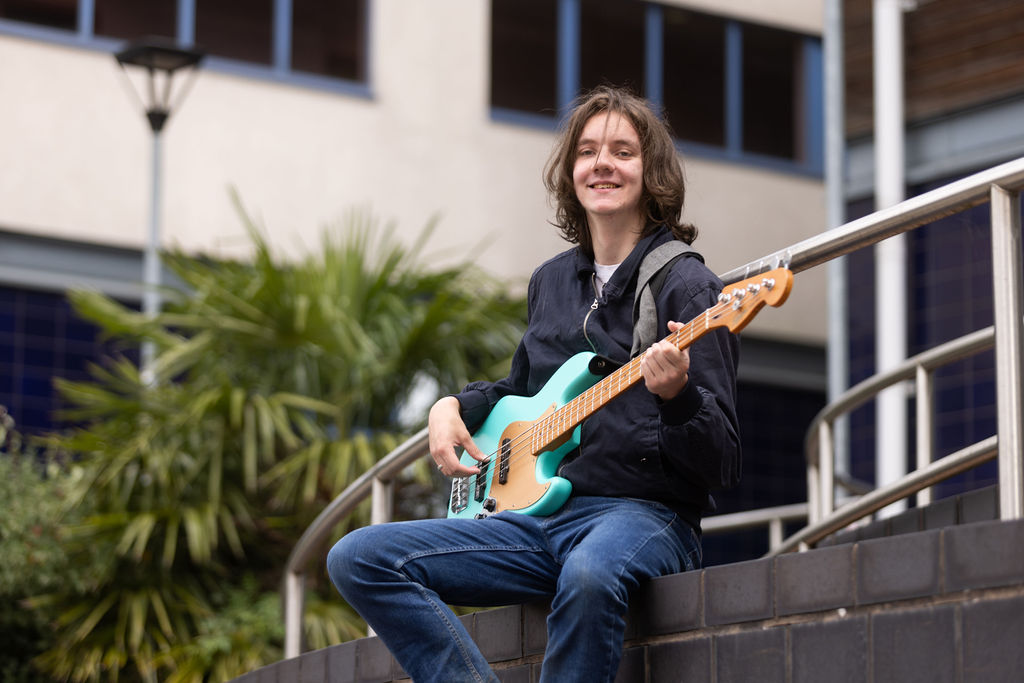 Declan Dean playing his guitar outside of the Joseph Wright Centre.