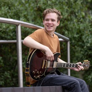 Owen Doherty playing his guitar outside of the Joseph Wright Centre.