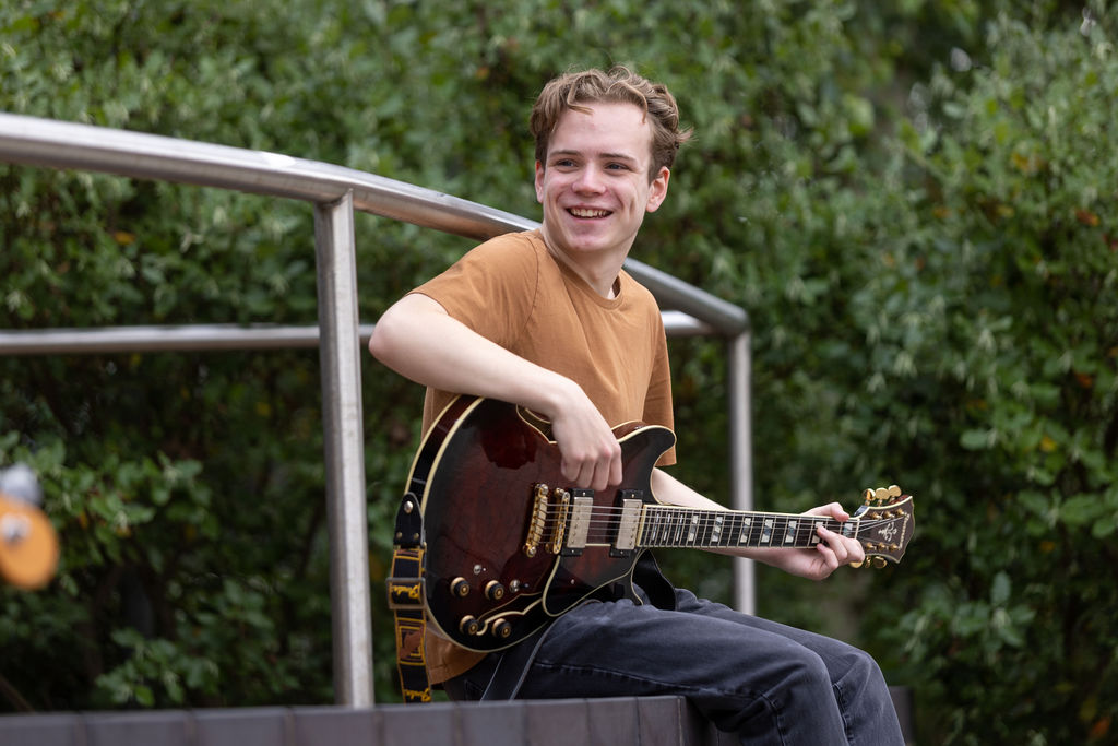 Owen Doherty playing his guitar outside of the Joseph Wright Centre.