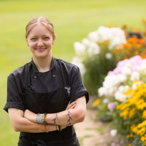 Derby College apprentice Chloe Cross stood next to a bed of flowers.