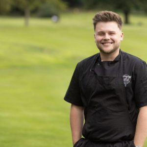 Former Derby College apprentice Tom Gaskell stood in a garden.