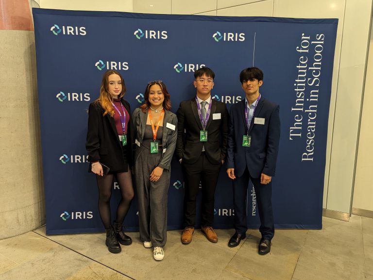 Four students at the IRIS Awards stood against a blue backdrop.