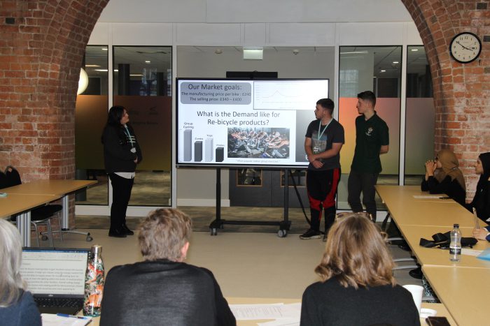 Three students presenting their idea to a panel of judges.