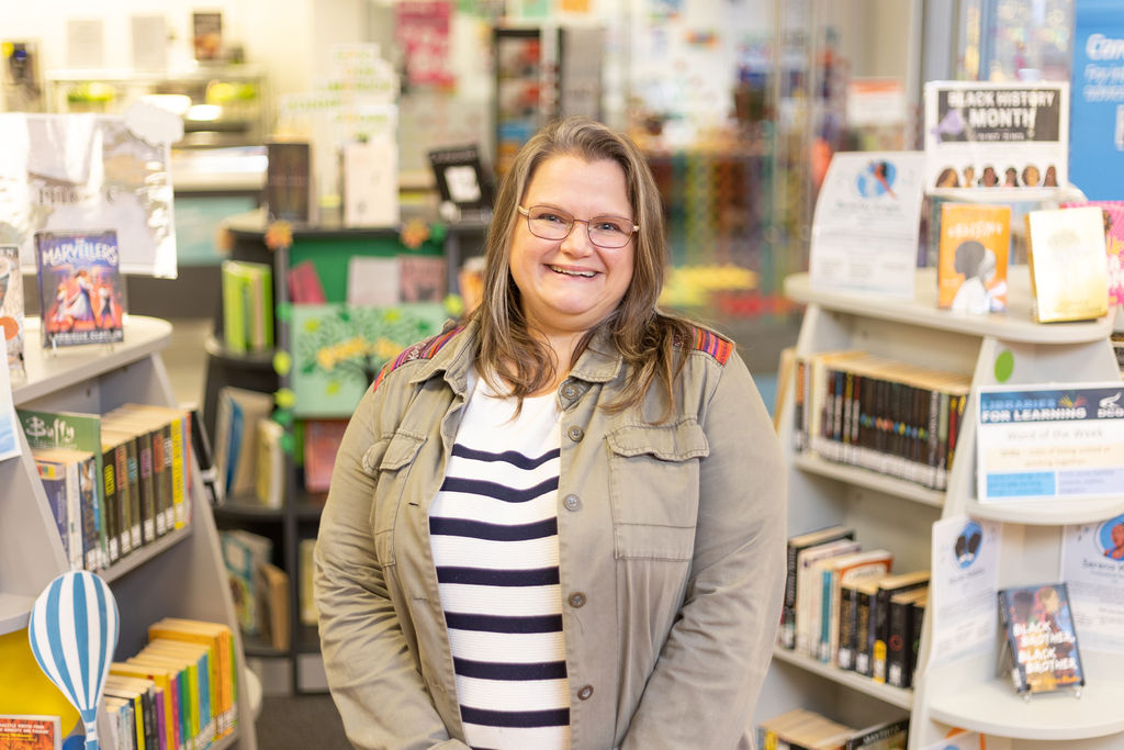 Lady with glasses and shoulder length hair in a library.