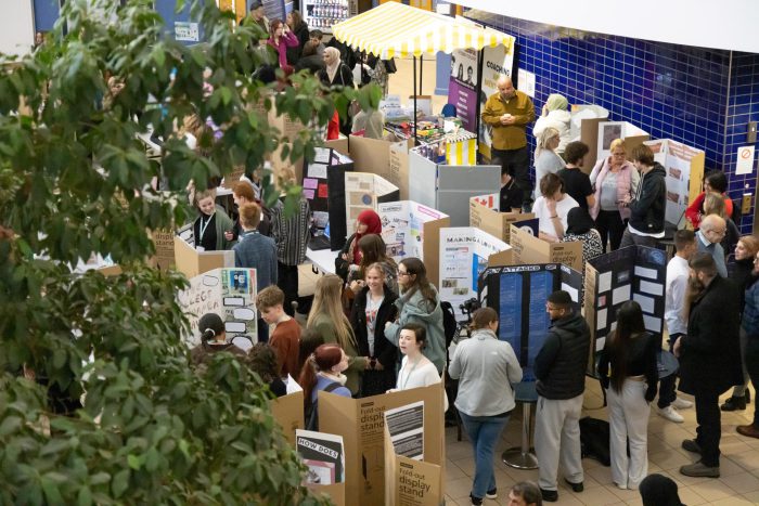 People in a big room looking at students' projects.