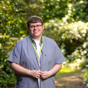 Roman Morley stood smiling by a bush.