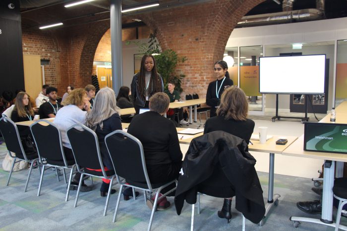 Two students presenting their product to the panel of judges.