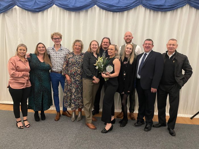 A large group of Derby College staff and students at an award ceremony.