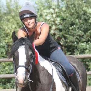 Female horse rider sat atop a horse.