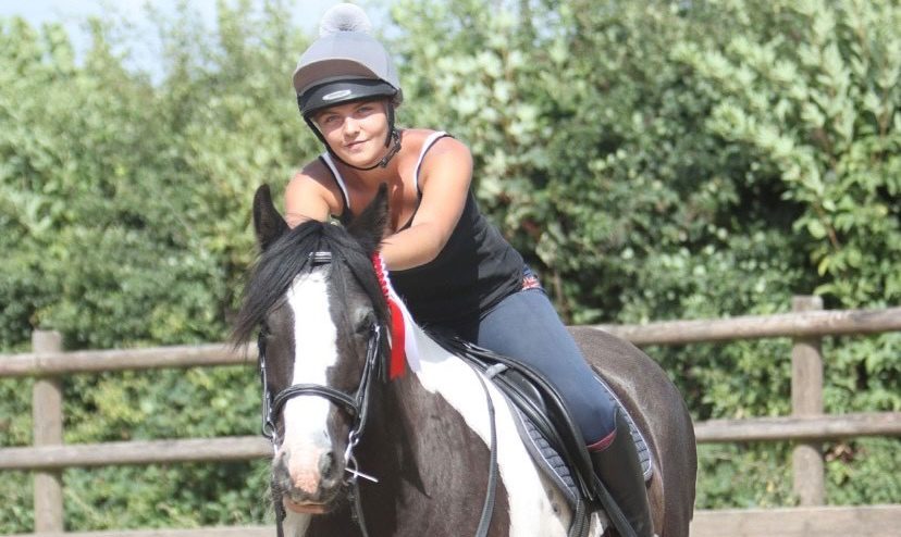 Female horse rider sat atop a horse.