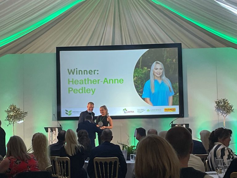 Female collecting an award at an award ceremony.