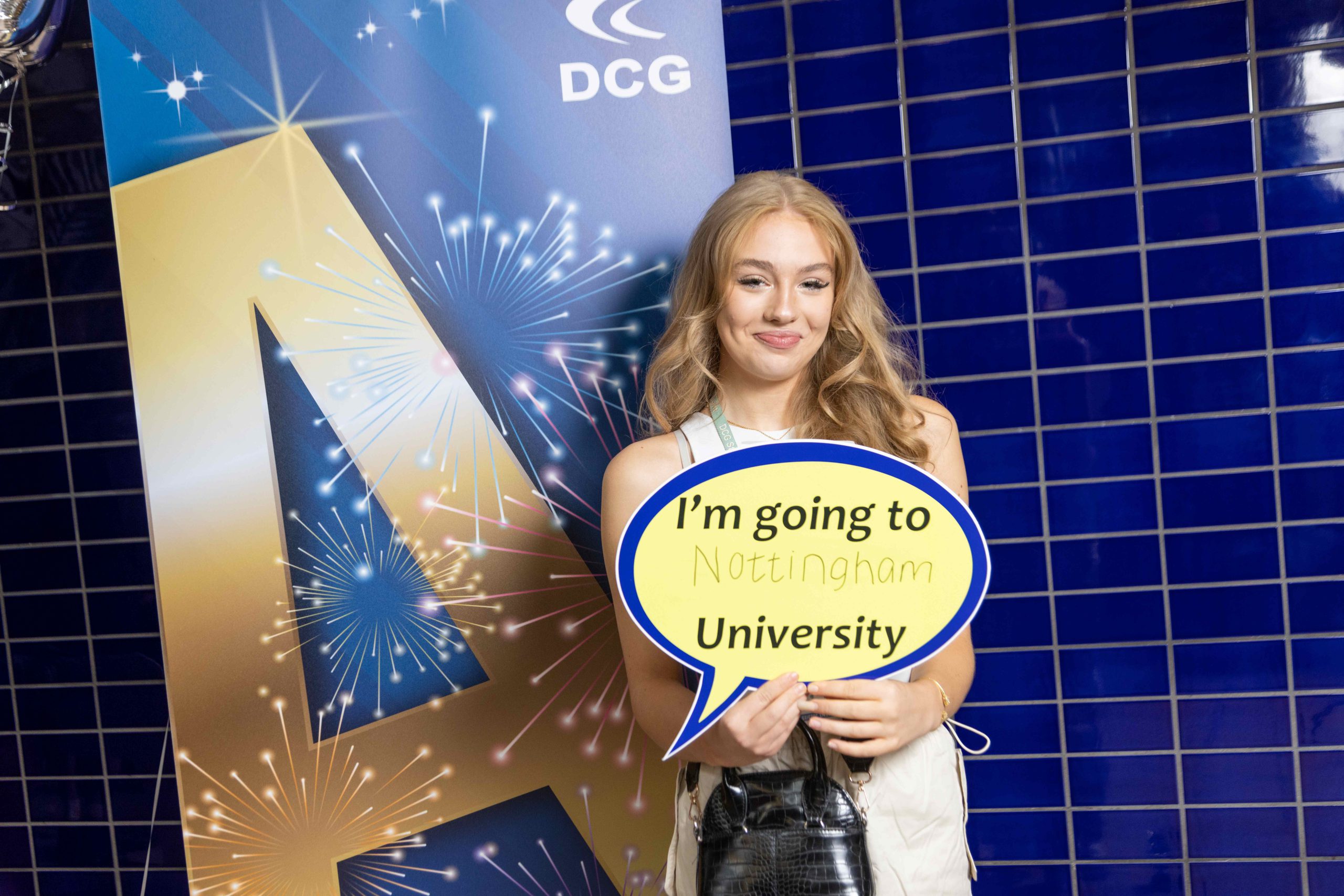 Young female with blonde hair holding a sign that reads 'I'm going to Nottingham University'.