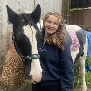 Female horserider with her arm around a horse.