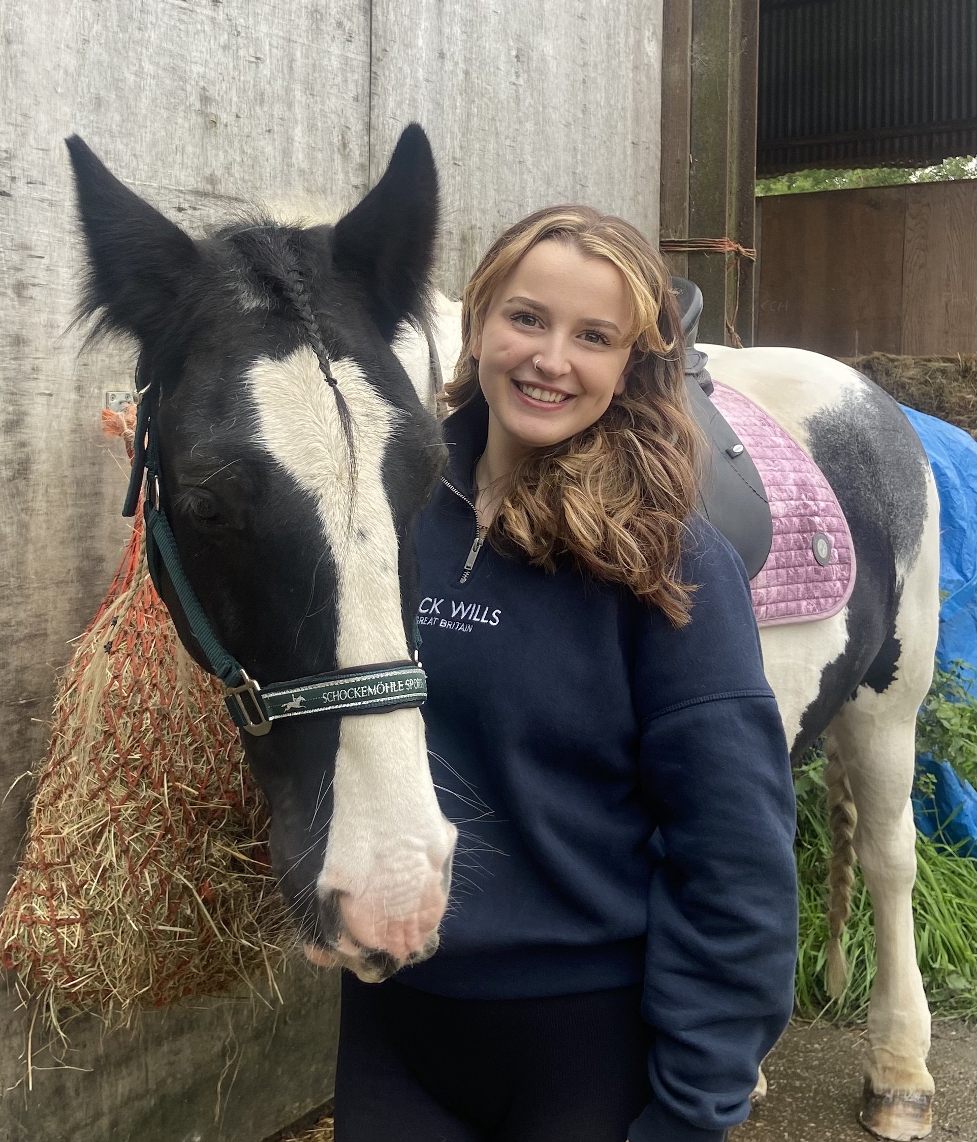 Female horserider with her arm around a horse.