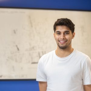 Former apprentice Shabaz Baz stood in front of a whiteboard wearing a white t-shirt.
