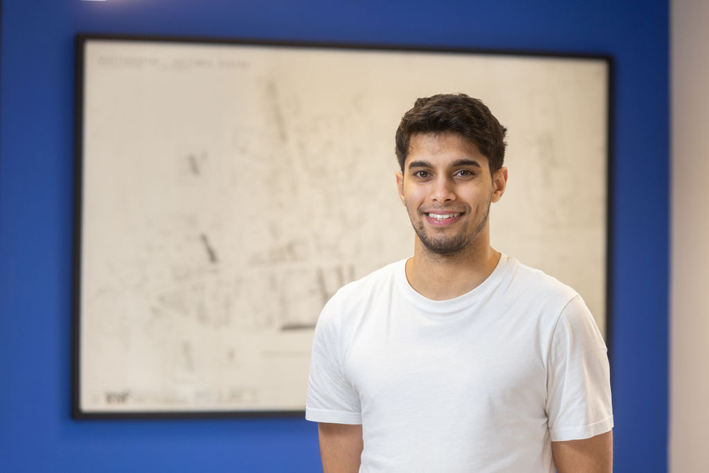 Former apprentice Shabaz Baz stood in front of a whiteboard wearing a white t-shirt.