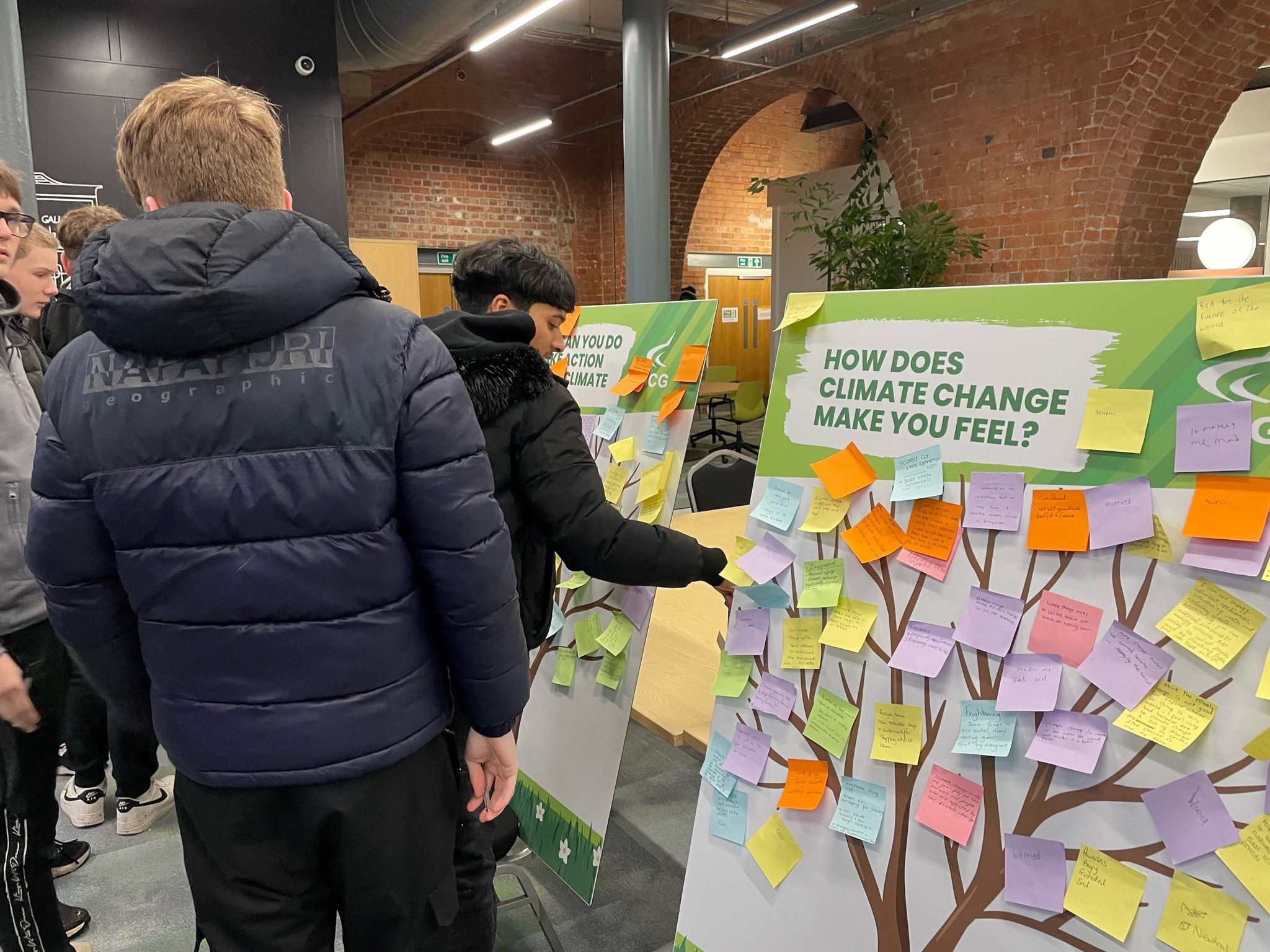 Students attaching post it notes to climate change board